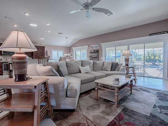 living room featuring tile patterned floors, ceiling fan, a textured ceiling, and vaulted ceiling