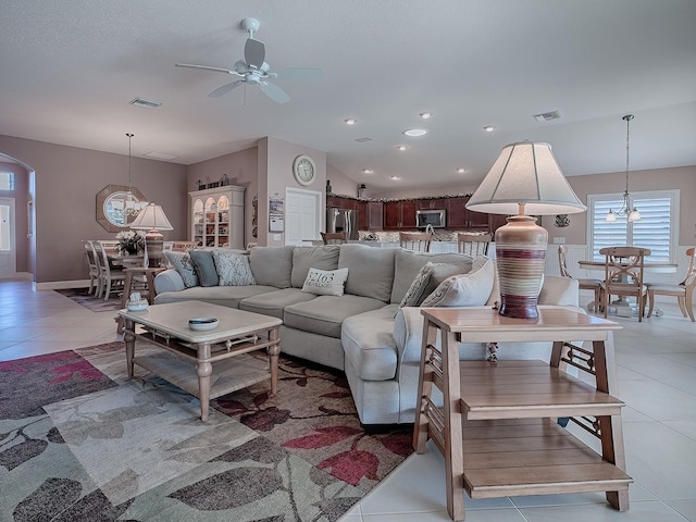 living room featuring lofted ceiling, light tile patterned floors, and ceiling fan with notable chandelier