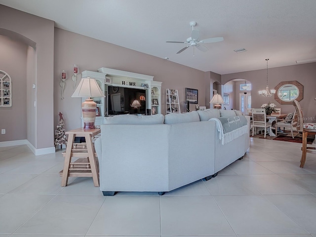 living room with light tile patterned floors, ceiling fan with notable chandelier, and a textured ceiling