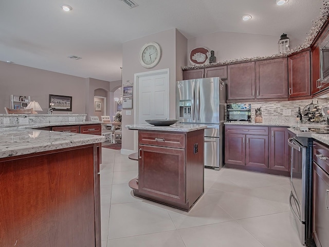 kitchen featuring light stone countertops, stainless steel appliances, light tile patterned floors, a center island, and lofted ceiling