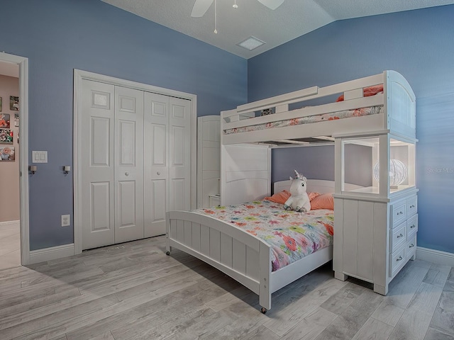 bedroom featuring light wood-type flooring, a closet, vaulted ceiling, and ceiling fan