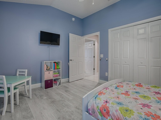 bedroom featuring ceiling fan, a closet, light hardwood / wood-style floors, and lofted ceiling