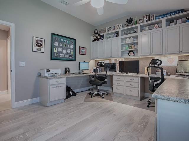 office area with ceiling fan, built in desk, light hardwood / wood-style flooring, and vaulted ceiling