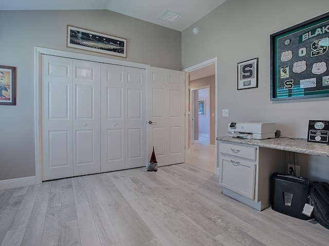 interior space with light hardwood / wood-style floors, built in desk, white cabinetry, and vaulted ceiling