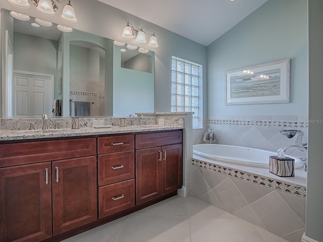 bathroom featuring tile patterned flooring, vanity, tiled bath, and lofted ceiling