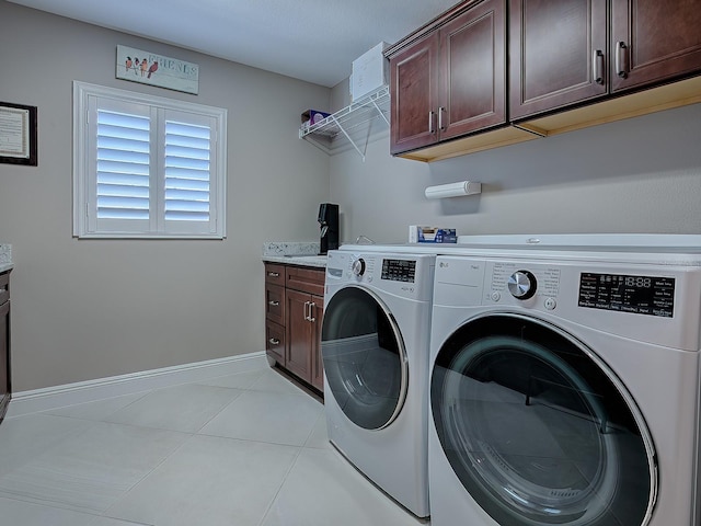 laundry room with washer and clothes dryer, light tile patterned floors, and cabinets