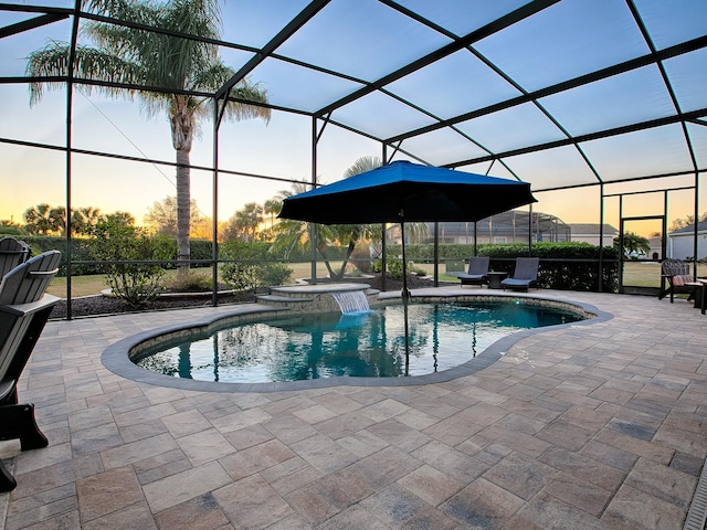 pool at dusk with a lanai, an in ground hot tub, and a patio