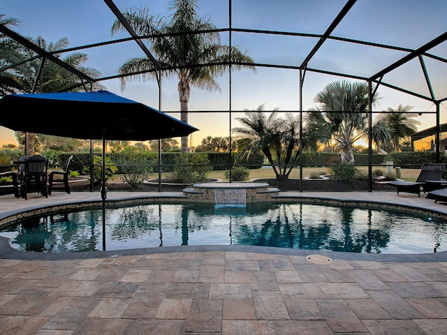 pool at dusk with a lanai, a patio area, and an in ground hot tub