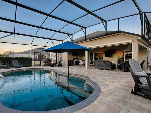 pool at dusk featuring glass enclosure and a patio area