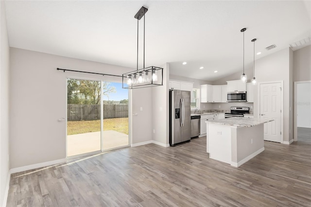 kitchen featuring white cabinetry, light stone counters, decorative light fixtures, a kitchen island, and appliances with stainless steel finishes