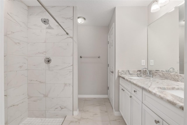 bathroom with a tile shower, vanity, and a textured ceiling