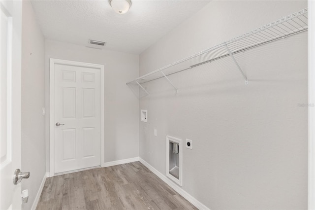 washroom with hookup for an electric dryer, washer hookup, light wood-type flooring, and a textured ceiling