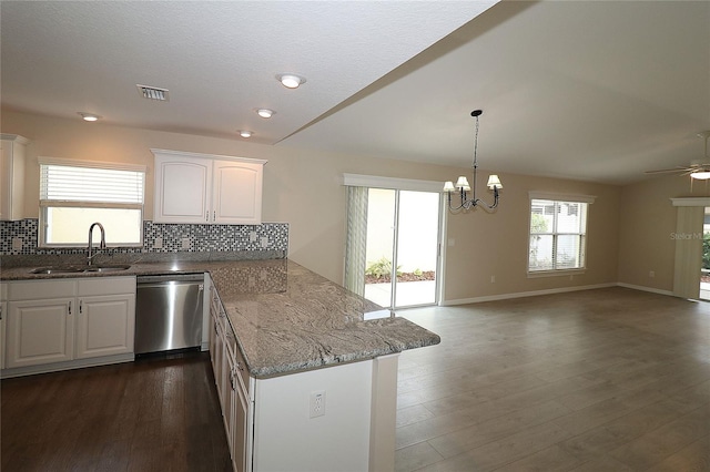 kitchen with light stone counters, stainless steel dishwasher, ceiling fan with notable chandelier, sink, and white cabinets