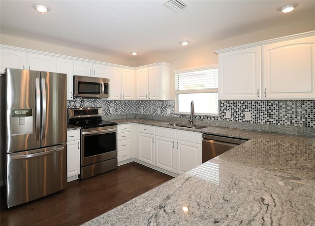 kitchen featuring stone counters, stainless steel appliances, white cabinetry, and sink