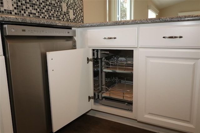 interior details featuring white cabinets, decorative backsplash, and dark stone counters