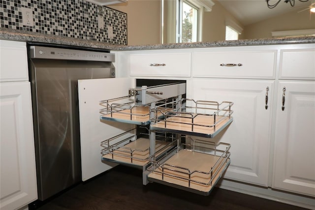 interior space with tasteful backsplash, white cabinetry, stainless steel dishwasher, and dark stone countertops