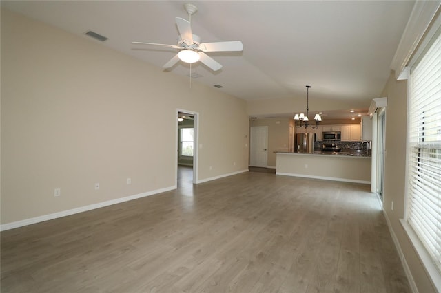 unfurnished living room featuring lofted ceiling, hardwood / wood-style floors, and ceiling fan with notable chandelier