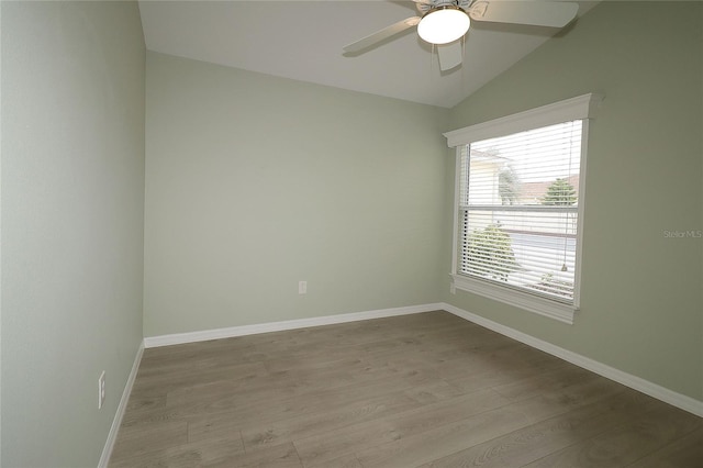 empty room with ceiling fan, light wood-type flooring, and vaulted ceiling