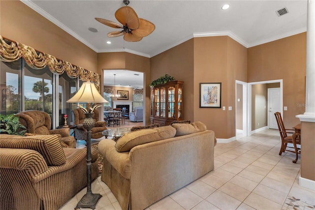 tiled living room with ceiling fan with notable chandelier and ornamental molding