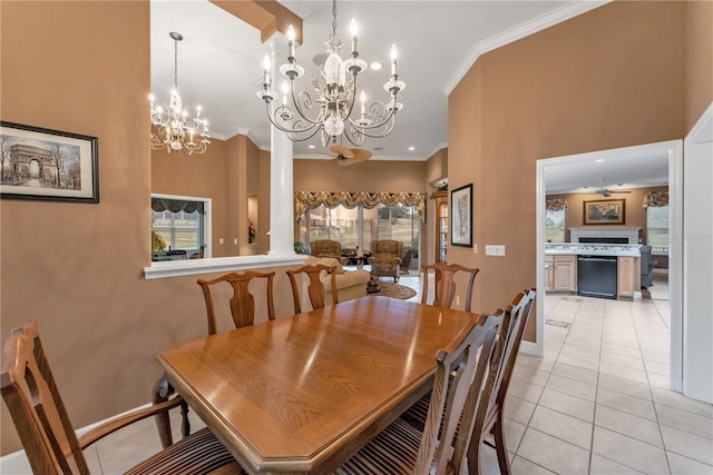 dining area with ceiling fan with notable chandelier, light tile patterned floors, crown molding, and ornate columns