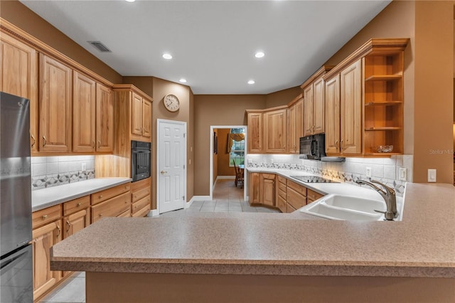 kitchen featuring black appliances, kitchen peninsula, sink, and tasteful backsplash