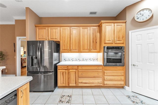 kitchen featuring appliances with stainless steel finishes, light brown cabinets, tasteful backsplash, light tile patterned flooring, and crown molding