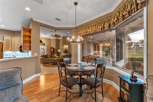 dining space with ceiling fan with notable chandelier, plenty of natural light, light hardwood / wood-style flooring, and crown molding