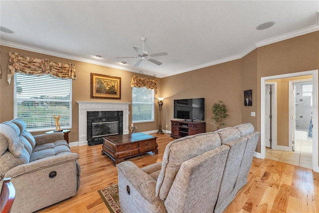 living room with light hardwood / wood-style floors, a high end fireplace, crown molding, and ceiling fan