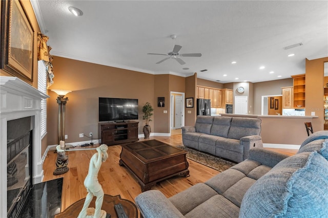 living room with ceiling fan, ornamental molding, and light wood-type flooring