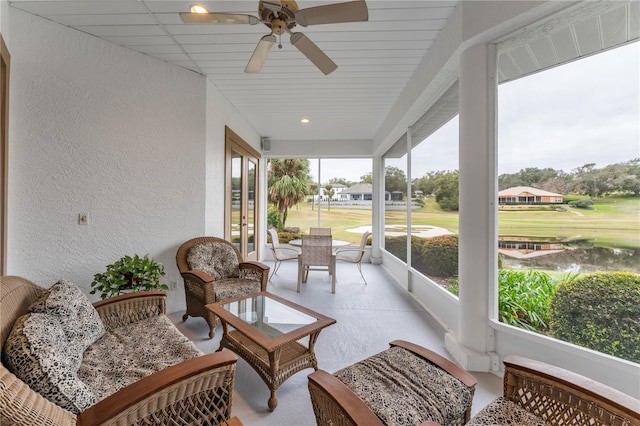 sunroom / solarium with ceiling fan and a water view