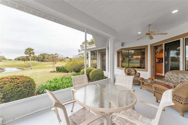 sunroom with ceiling fan and a water view