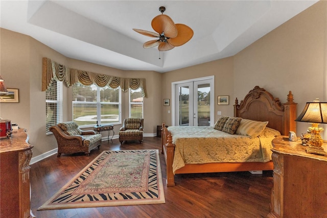 bedroom with ceiling fan, access to exterior, dark hardwood / wood-style floors, a tray ceiling, and french doors