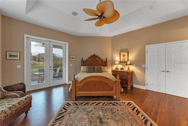 bedroom with access to outside, french doors, dark hardwood / wood-style floors, and a tray ceiling