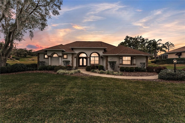 mediterranean / spanish-style house with a lawn and french doors