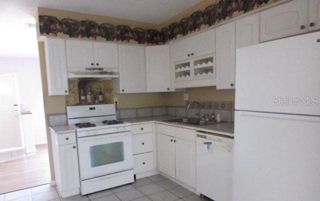 kitchen featuring sink, exhaust hood, light tile patterned floors, white appliances, and white cabinets