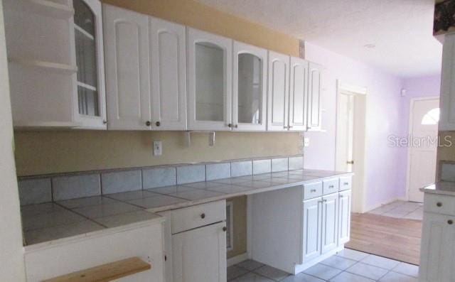 kitchen with white cabinetry, tile counters, and light tile patterned floors