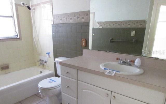 full bathroom featuring tiled shower / bath combo, vanity, a wealth of natural light, and toilet