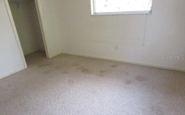 unfurnished bedroom featuring light colored carpet and a closet