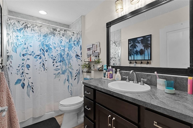 bathroom with hardwood / wood-style floors, vanity, a shower with shower curtain, toilet, and a textured ceiling