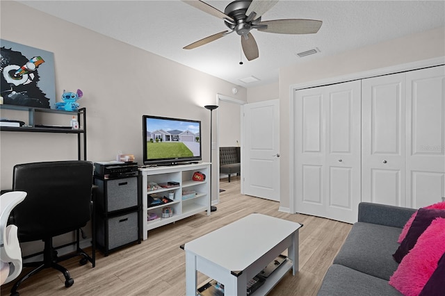 home office with ceiling fan, light hardwood / wood-style floors, and a textured ceiling