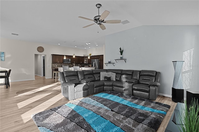 living room featuring ceiling fan, lofted ceiling, and light wood-type flooring