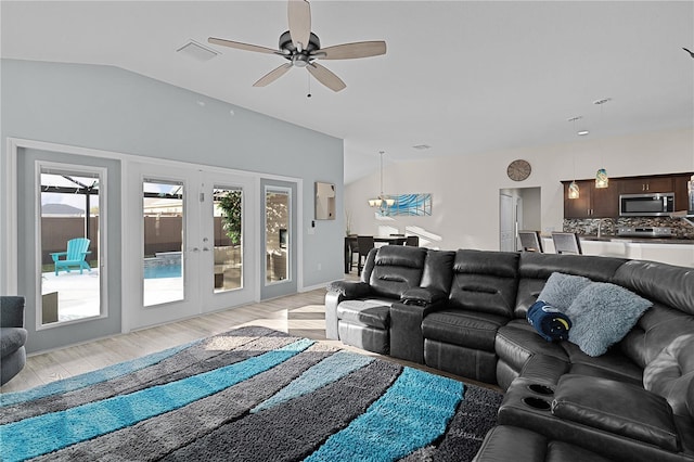 living room featuring ceiling fan, light hardwood / wood-style flooring, and vaulted ceiling