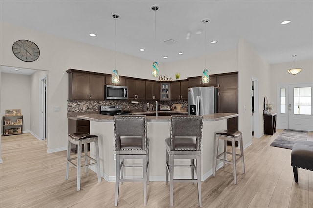 kitchen featuring pendant lighting, dark brown cabinetry, stainless steel appliances, and a center island with sink