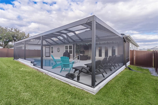 rear view of house with glass enclosure, a fenced in pool, a yard, and a patio