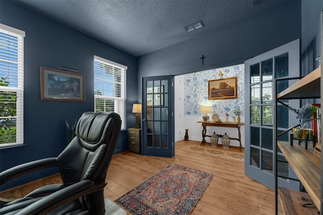 office space with a textured ceiling, french doors, and light hardwood / wood-style flooring