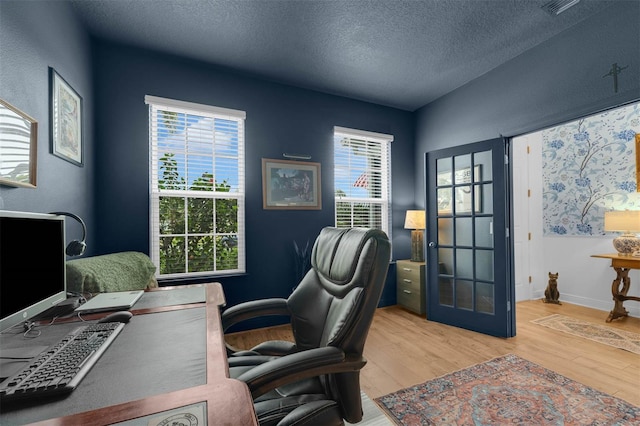 office with a textured ceiling and light wood-type flooring