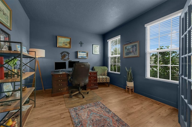 office space featuring a textured ceiling and light wood-type flooring