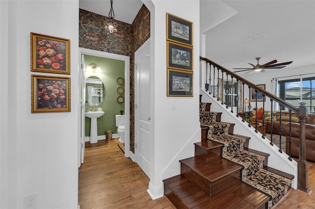 stairway with ceiling fan and wood-type flooring