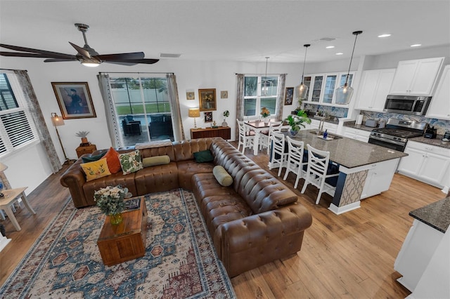 living room featuring light wood-type flooring, ceiling fan, and sink