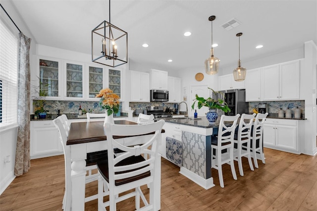 kitchen featuring a breakfast bar area, tasteful backsplash, a kitchen island with sink, and appliances with stainless steel finishes